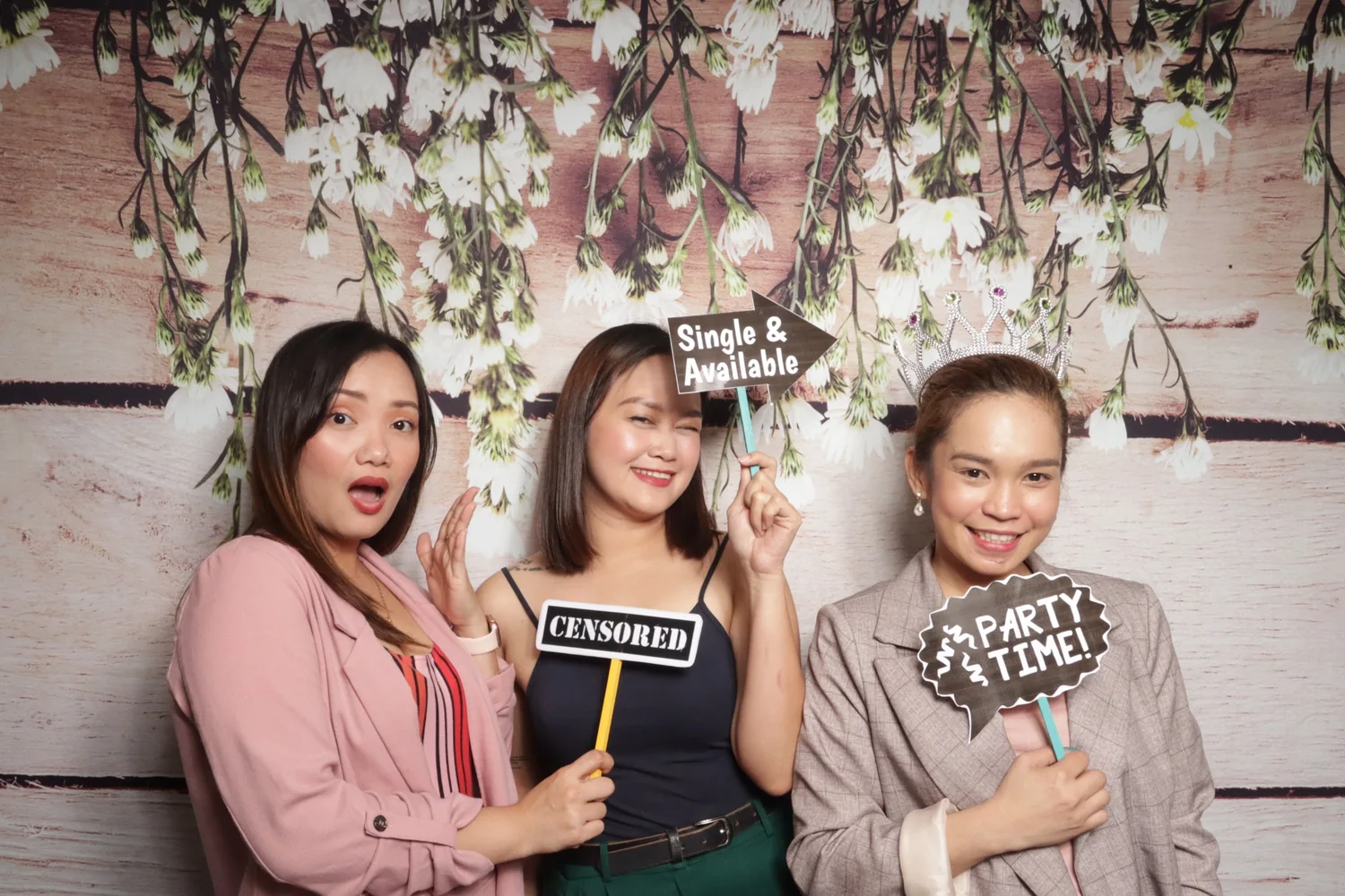 Friends posing together at a floral photo booth